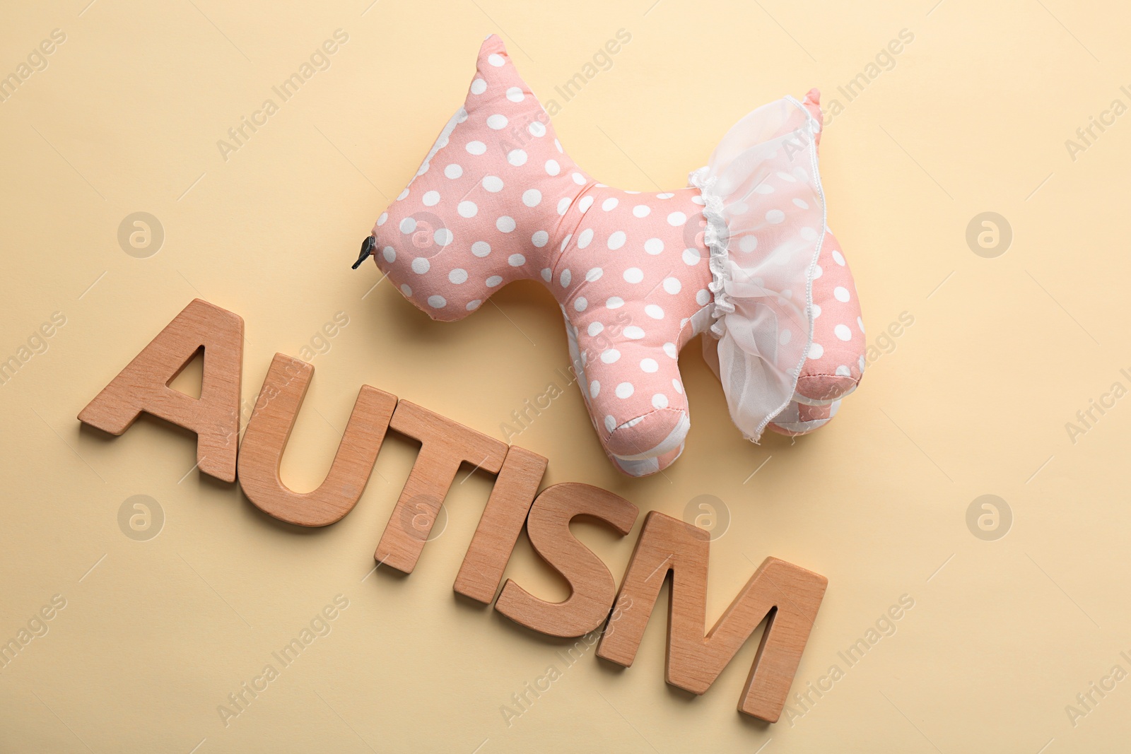Photo of Word "Autism" and toy on color background
