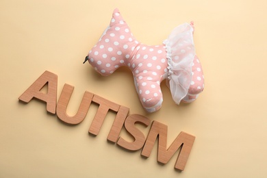 Photo of Word "Autism" and toy on color background