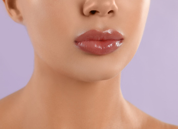 Photo of Young woman with beautiful full lips on lilac background, closeup