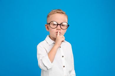 Photo of Portrait of cute little boy in glasses on light blue background