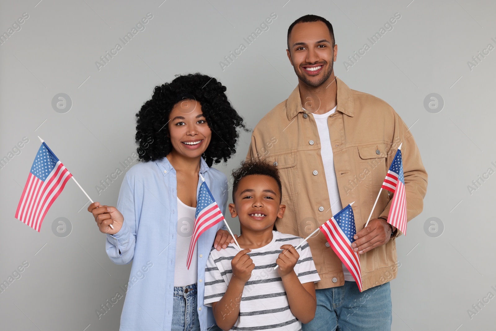 Photo of 4th of July - Independence Day of USA. Happy family with American flags on light grey background
