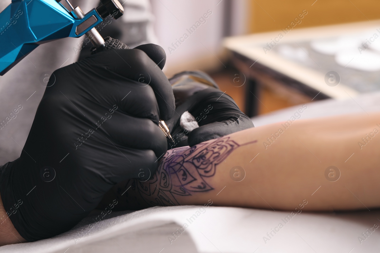 Photo of Professional artist making tattoo on hand in salon, closeup