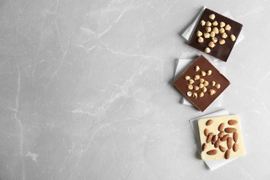 Photo of Different chocolate bars with nuts on grey background