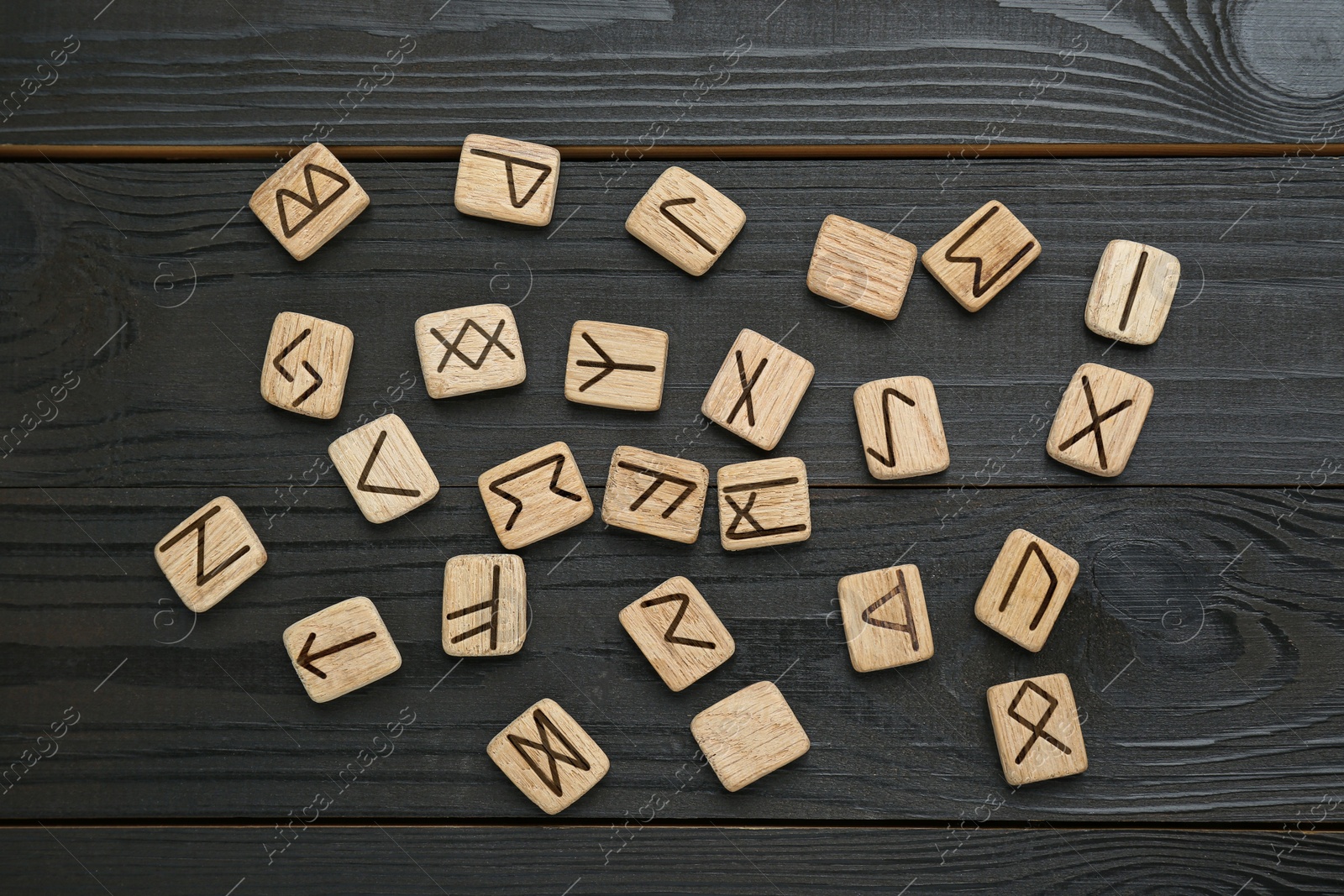 Photo of Runes with different symbols on black wooden table, flat lay