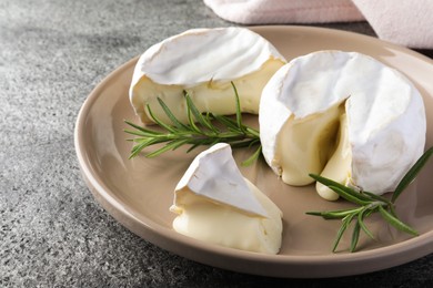 Photo of Delicious brie cheese with rosemary on grey table, closeup