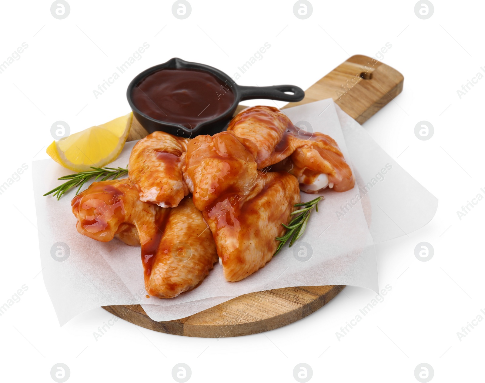 Photo of Board with marinade, raw chicken wings, rosemary and lemon isolated on white