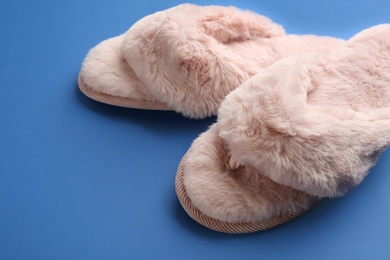 Photo of Pair of stylish soft slippers on blue background, closeup