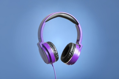 Stylish headphones with pads on color background