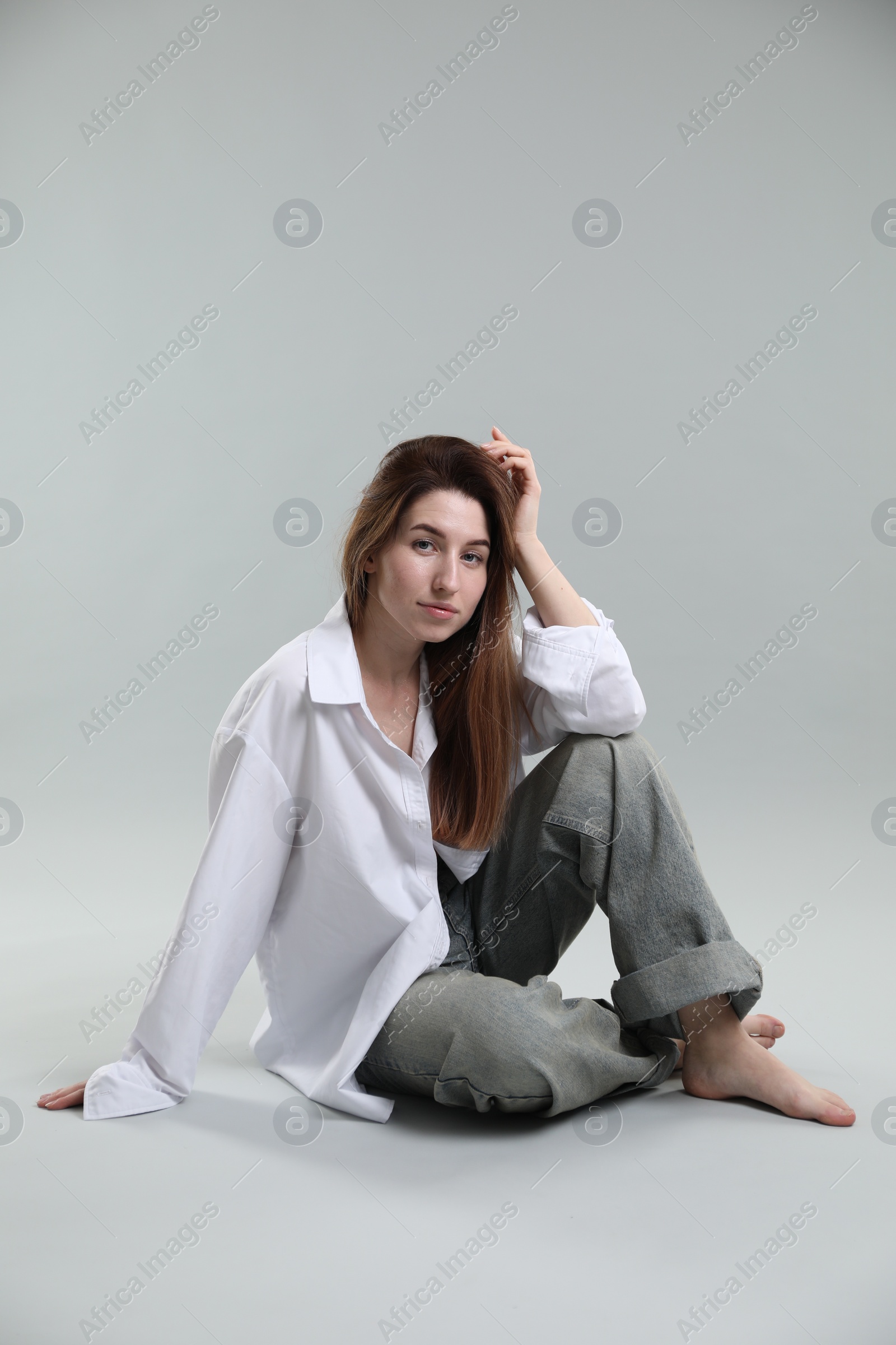 Photo of Beautiful young woman sitting on grey background