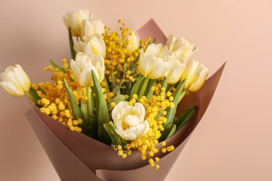 Photo of Bouquet of beautiful spring flowers near beige wall, closeup