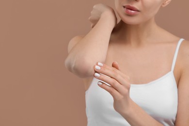 Photo of Woman with dry skin checking her elbow on beige background, closeup. Space for text