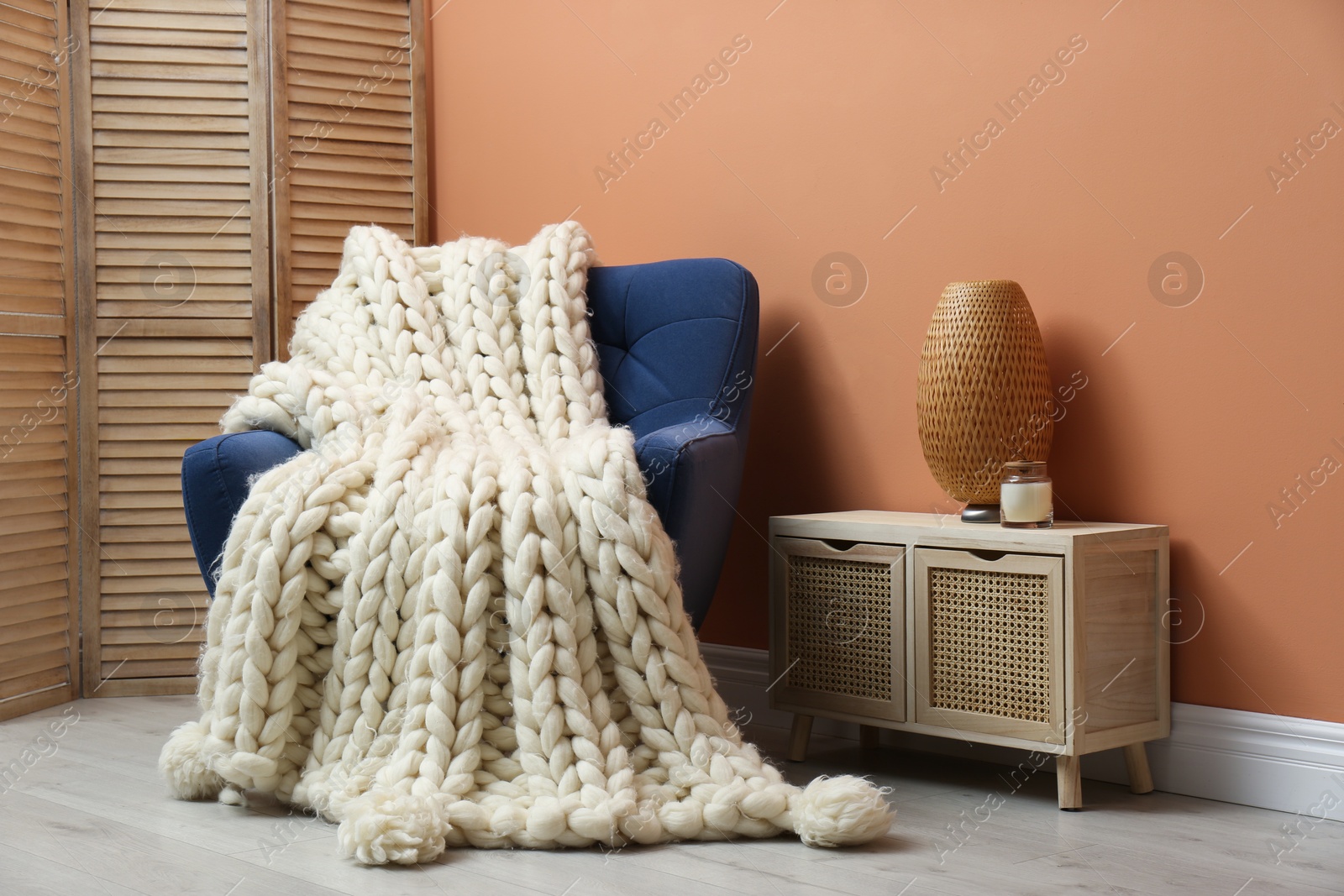 Photo of Knitted merino wool plaid on armchair in room