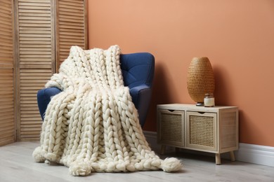 Photo of Knitted merino wool plaid on armchair in room