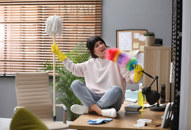 Photo of Lazy woman having fun while cleaning at home