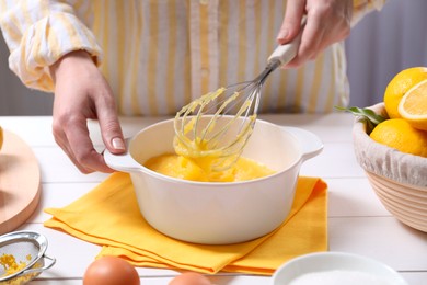 Photo of Woman cooking lemon curd at white wooden table, closeup