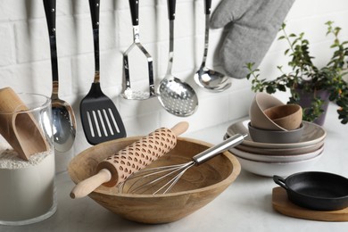 Photo of Different cooking utensils and plant on countertop in kitchen