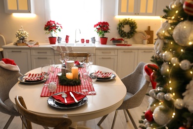 Photo of Table with dishware in beautiful kitchen interior decorated for Christmas