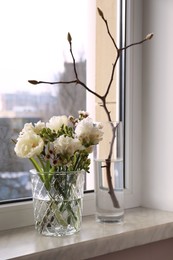 Beautiful spring flowers in vase on windowsill indoors