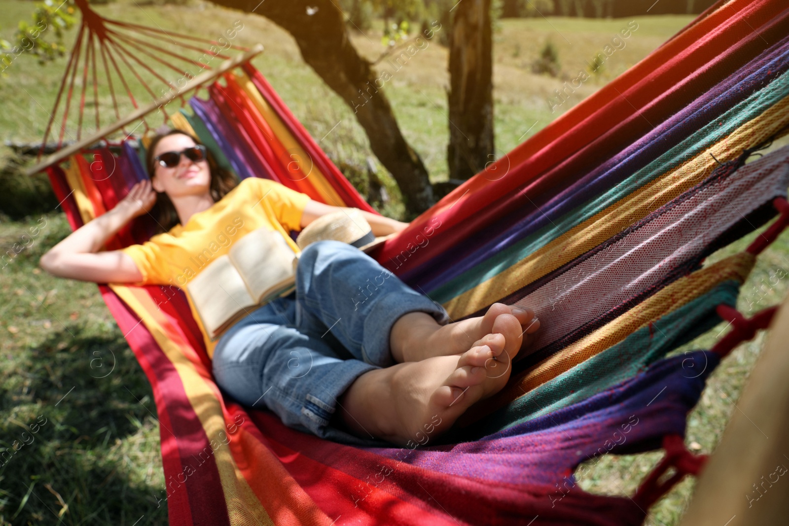 Photo of Woman resting in hammock outdoors, focus on legs