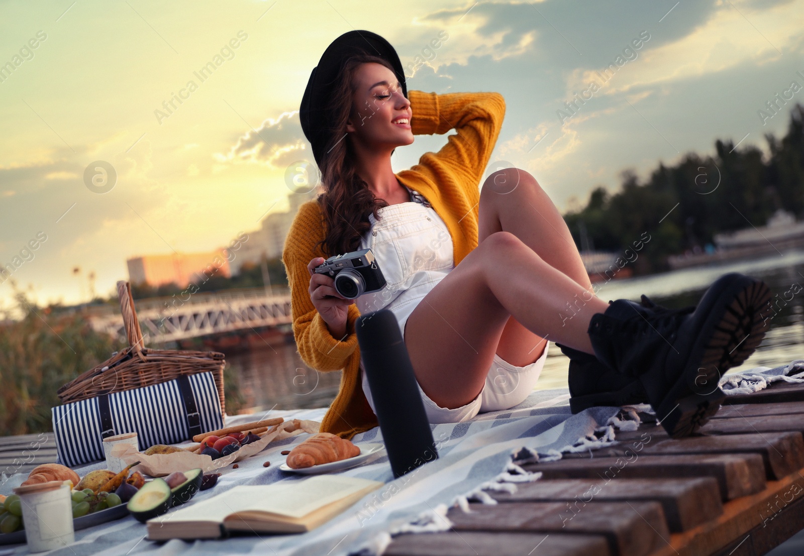 Photo of Young woman with camera on pier at picnic