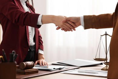 Notary shaking hands with client at table in office, closeup