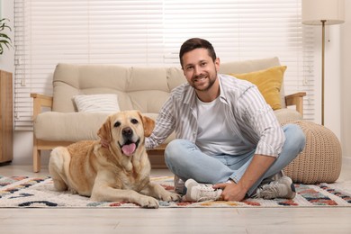 Photo of Man with adorable Labrador Retriever dog at home. Lovely pet