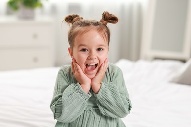 Portrait of emotional little girl in bedroom