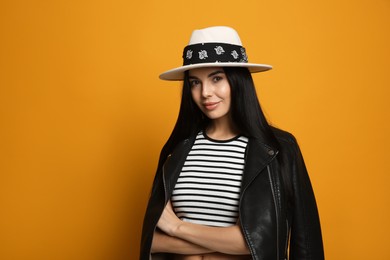 Photo of Fashionable young woman in stylish outfit with bandana on orange background, space for text