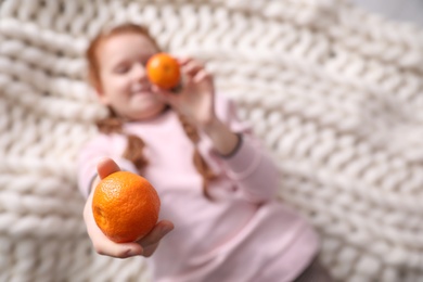 Little girl with tangerines, focus on hand. Space for text