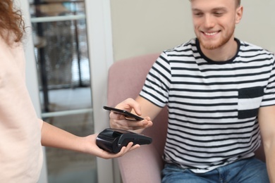 Client using smartphone and credit card machine for non cash payment in cafe