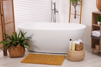 Photo of Stylish bathroom interior with soft bath mat and tub