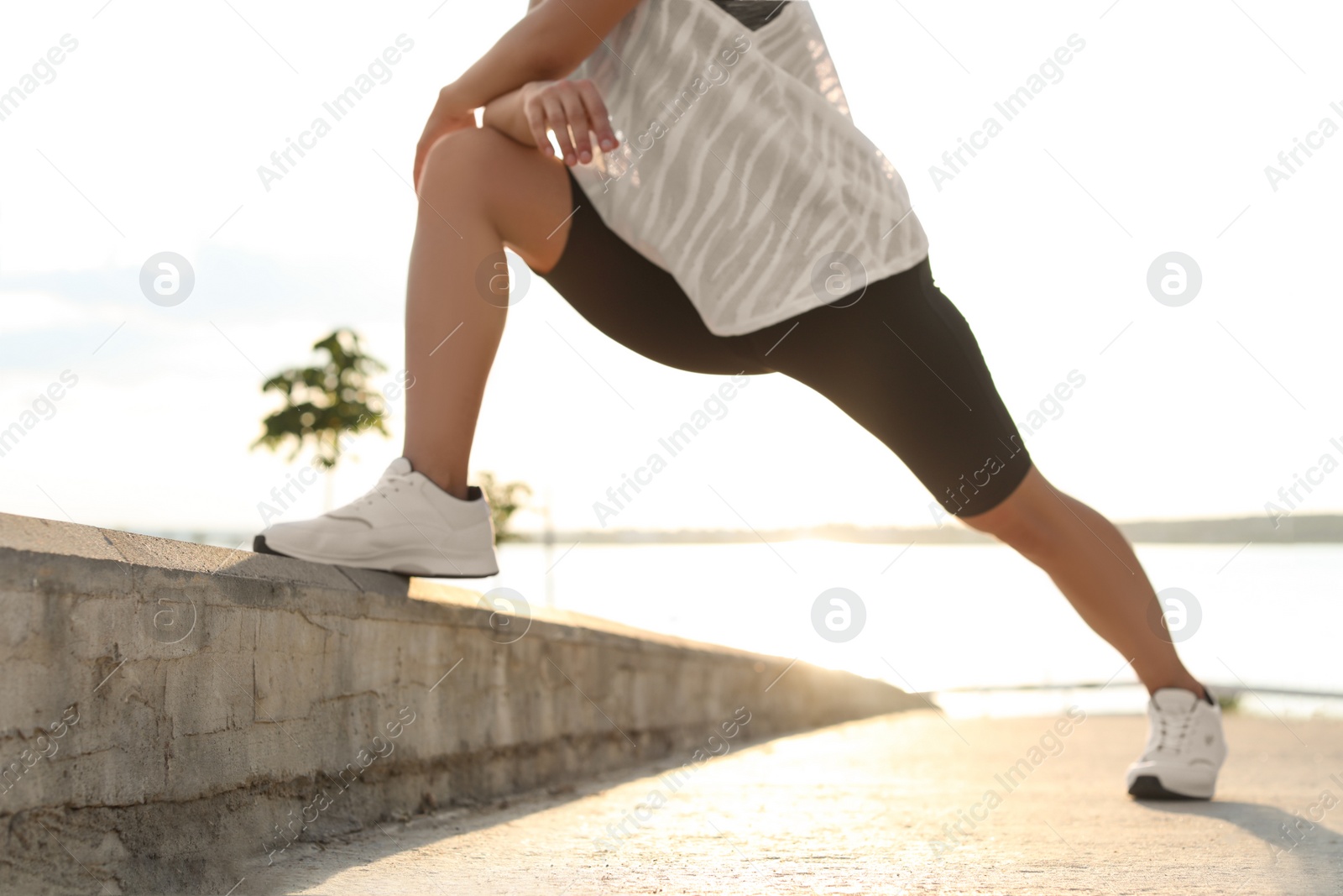 Photo of Young woman stretching outdoors in morning, closeup