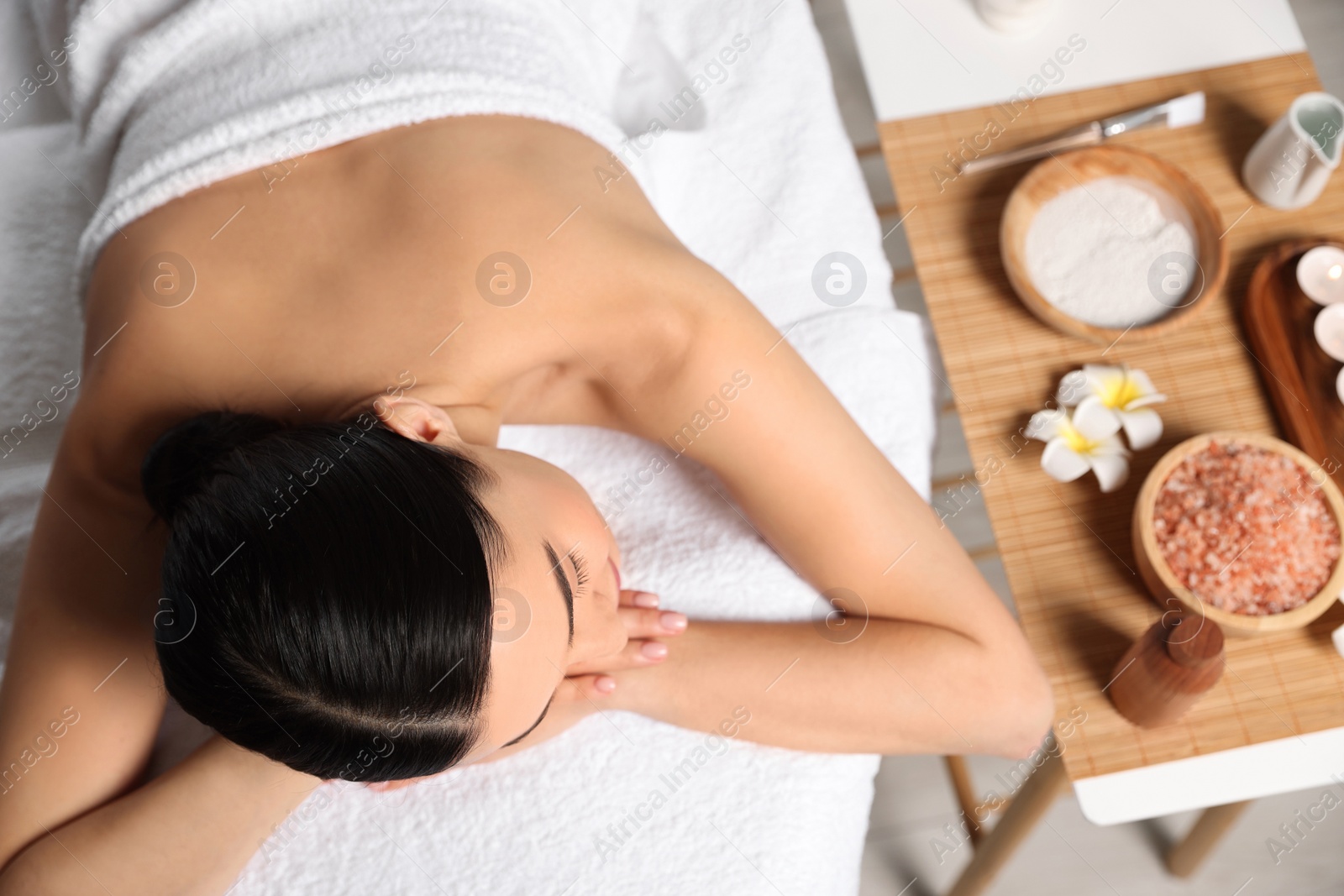 Photo of Beautiful woman relaxing on massage table in spa salon, above view