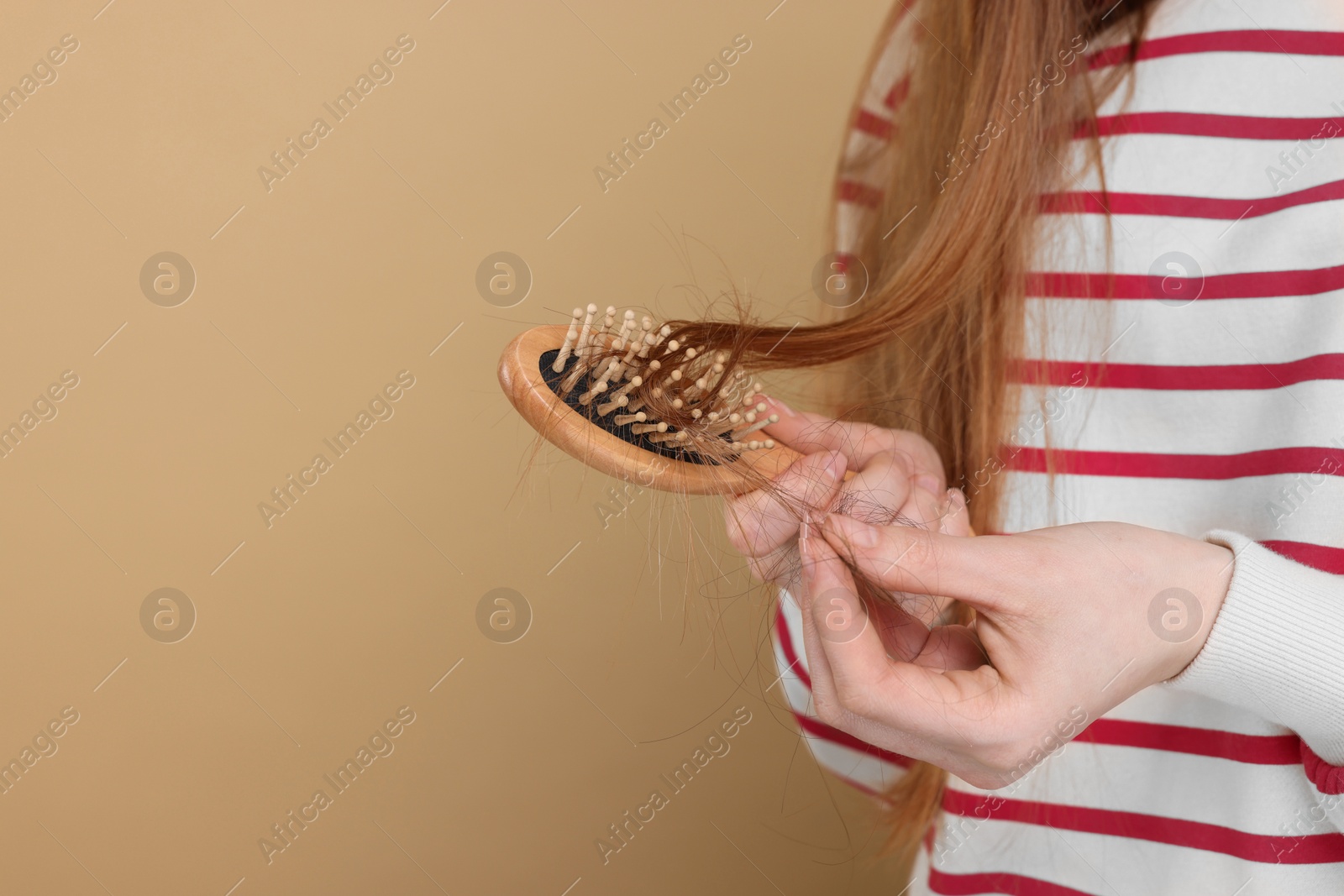 Photo of Woman brushing her hair on beige background, closeup and space for text. Alopecia problem