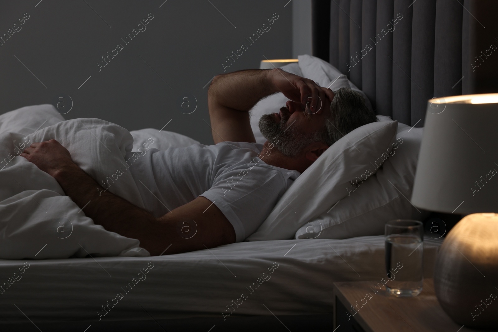 Photo of Mature man suffering from headache in bed at night