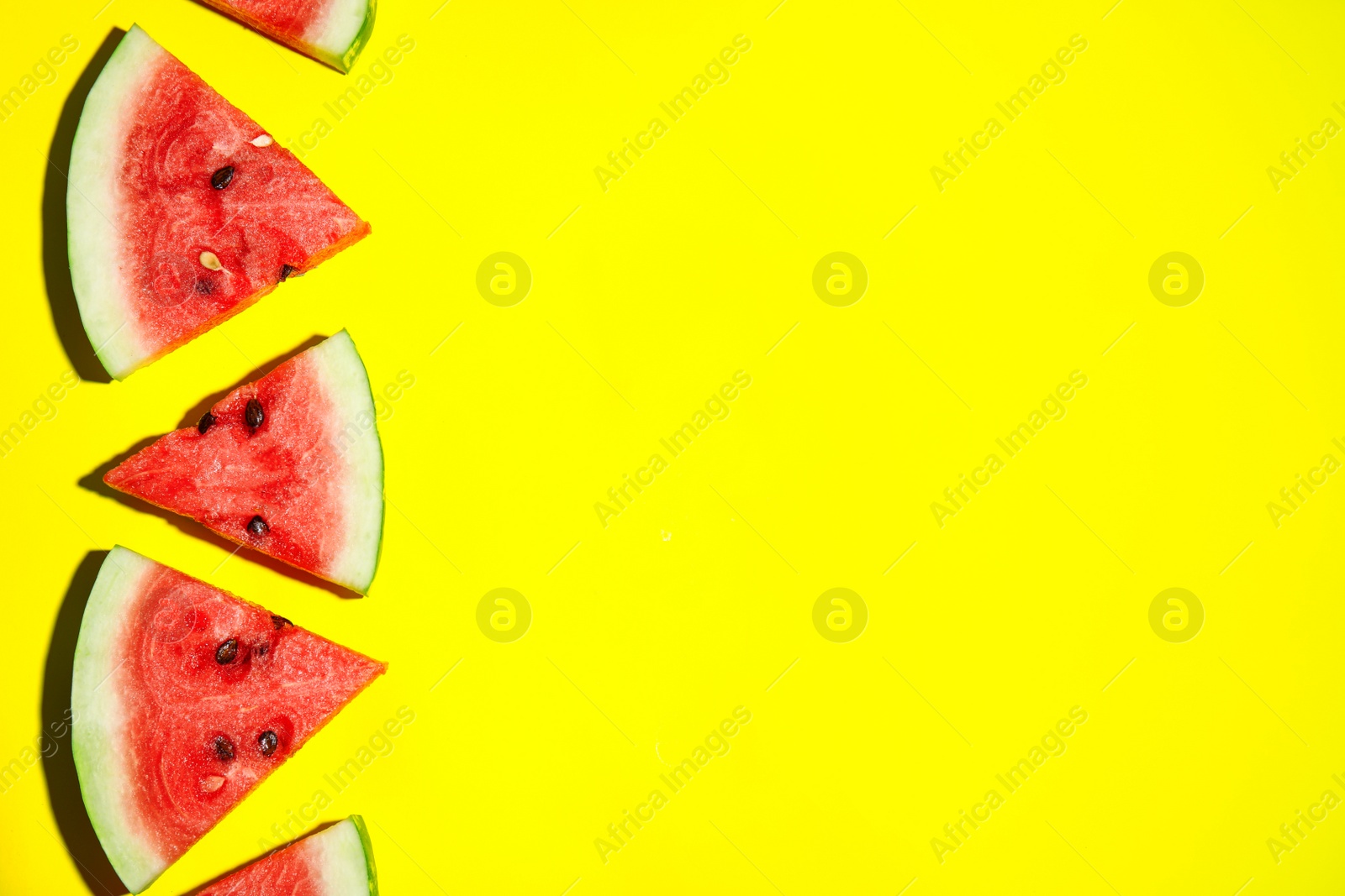 Photo of Watermelon slices on yellow background, flat lay. Space for text