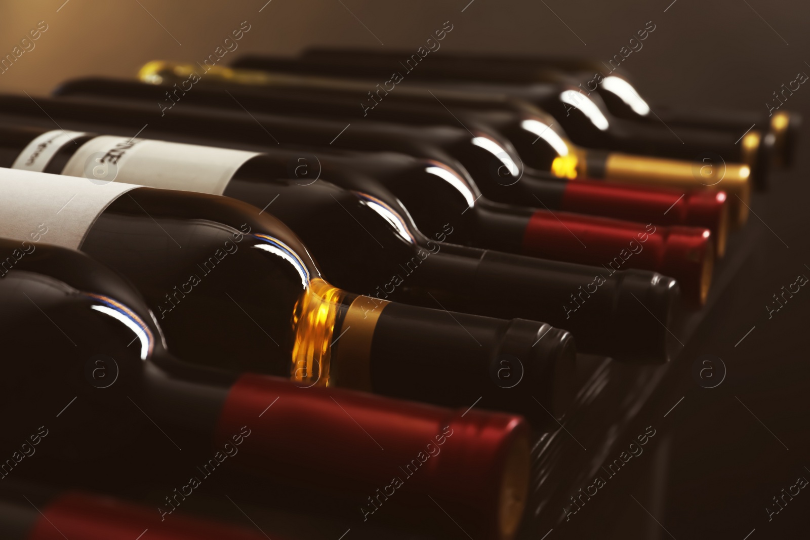 Photo of Bottles with delicious wine on shelf, closeup. Professional sommelier