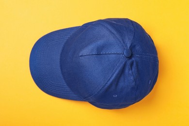 Stylish blue baseball cap on yellow background, top view