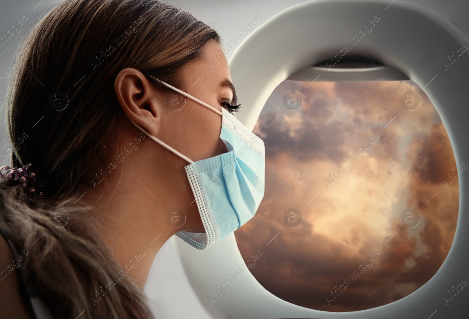 Image of Traveling by airplane during coronavirus pandemic. Woman with face mask near porthole