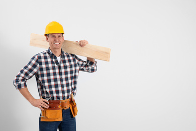 Photo of Handsome carpenter with wooden planks on light background. Space for text