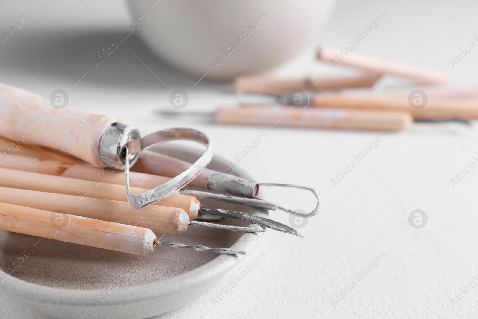 Photo of Set of different clay crafting tools on white table, closeup. Space for text