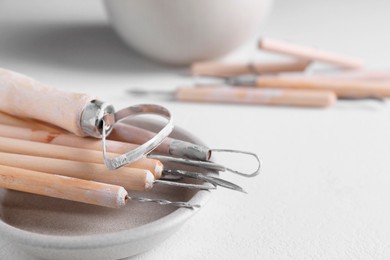 Photo of Set of different clay crafting tools on white table, closeup. Space for text