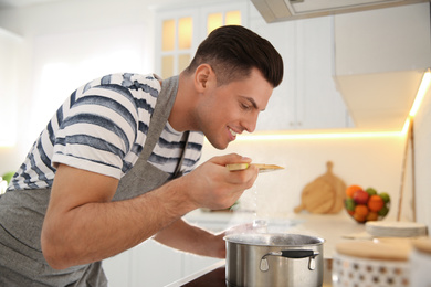 Photo of Handsome man cooking on stove in kitchen