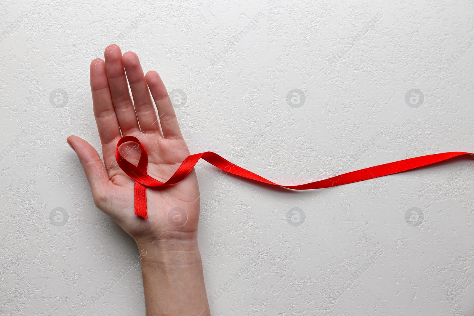 Photo of Woman holding red awareness ribbon on white background, top view with space for text. World AIDS disease day