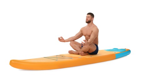 Photo of Handsome man practicing yoga on orange SUP board against white background