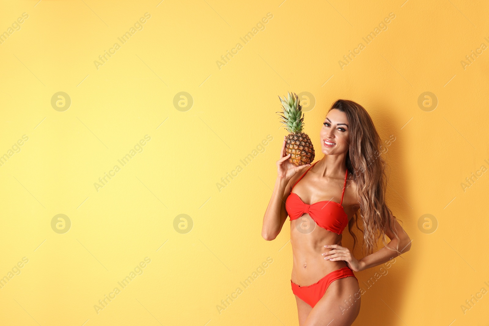 Photo of Pretty sexy woman in stylish bikini with pineapple on color background, space for text