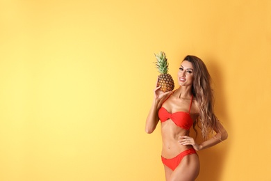 Pretty sexy woman in stylish bikini with pineapple on color background, space for text