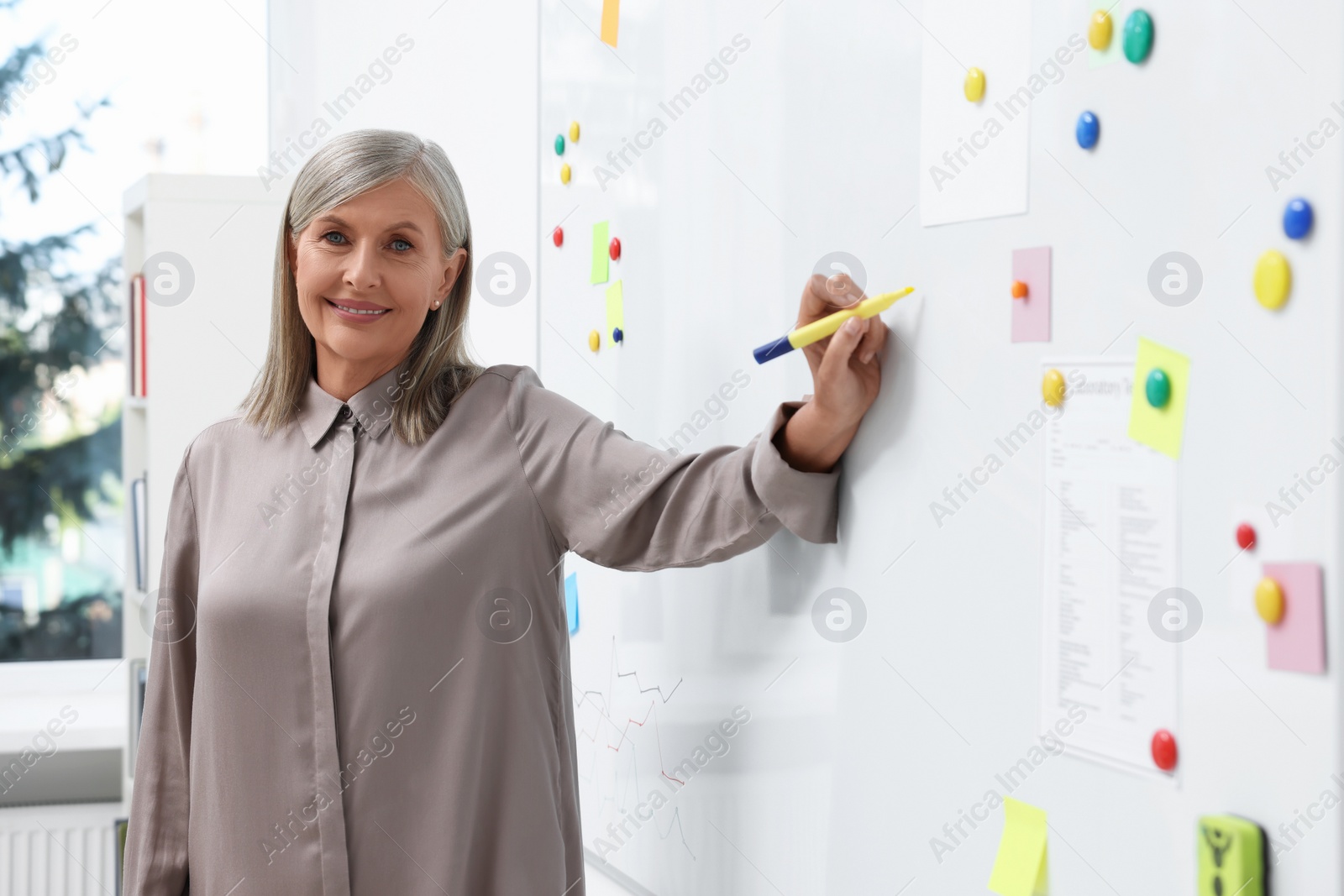 Photo of Professor explaining something with marker at whiteboard in classroom