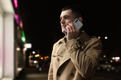 Photo of Man talking by smartphone on night city street, space for text