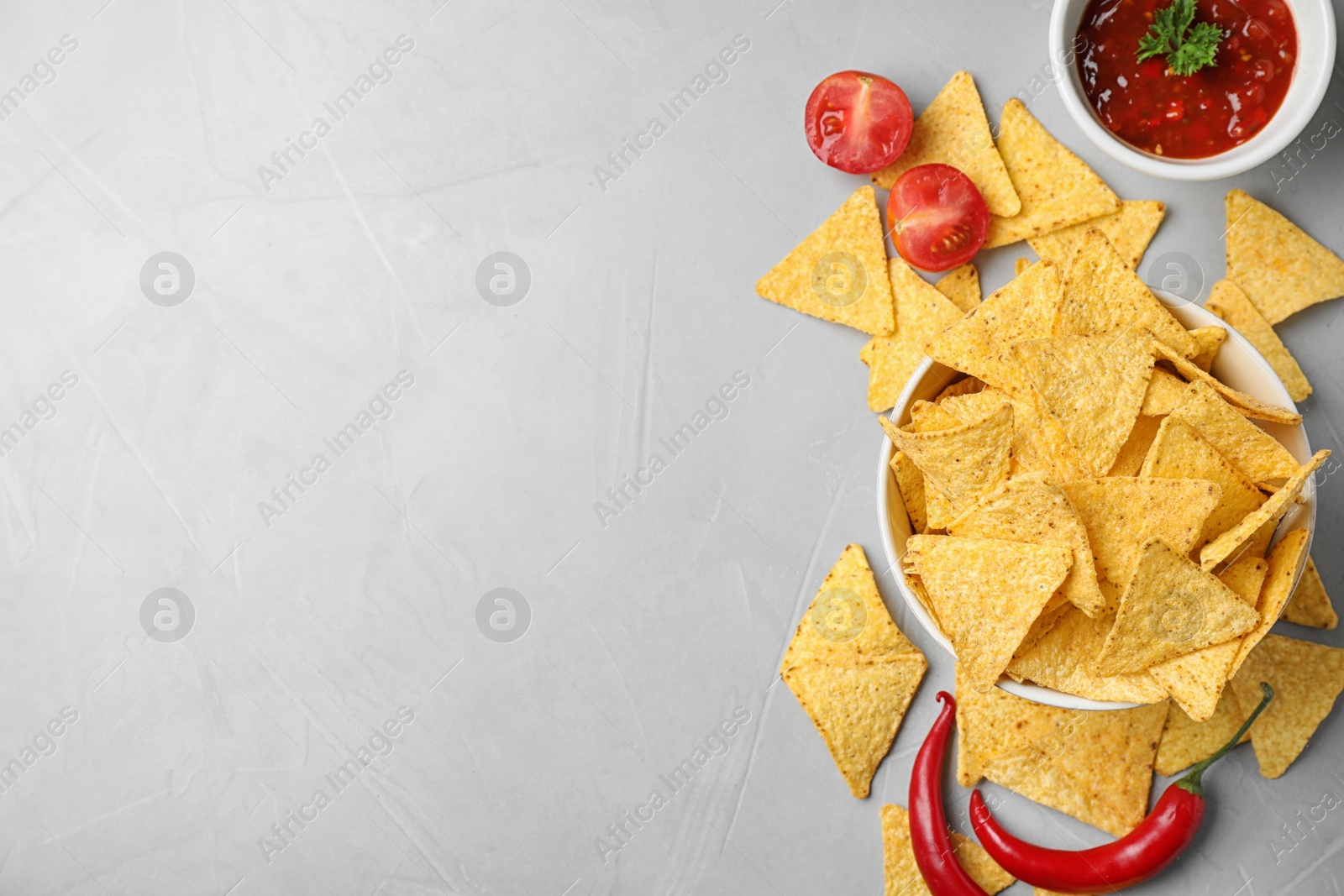 Photo of Flat lay composition with tasty Mexican nachos chips on grey table, space for text